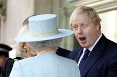 a man in a suit and hat talking to an older woman with her mouth open