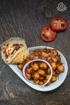 a white plate topped with food next to tomatoes and pita bread