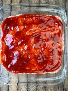 a glass dish filled with sauce on top of a wooden table