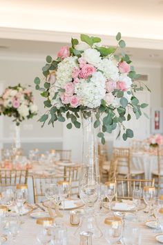 a tall vase filled with pink and white flowers on top of a dining room table