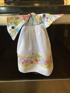 a white towel hanging from the handle of an oven with flowers on it and a bow