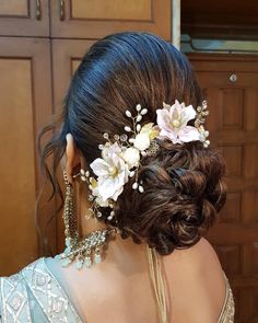 a woman wearing a hair comb with flowers on it's head and pearls in her hair