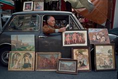 a man sitting in the back of a car surrounded by pictures