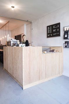 the front desk of a coffee shop with a woman sitting at it's counter