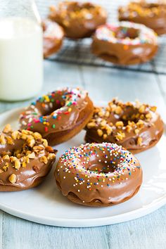 chocolate donuts with sprinkles on a plate next to a glass of milk