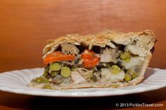 a piece of chicken pot pie on a white plate with a wooden table in the background