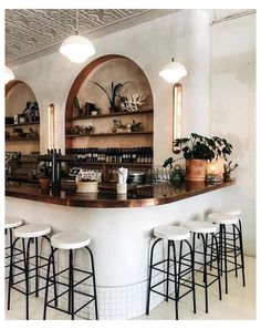 a bar with several stools and shelves filled with bottles on the wall behind it