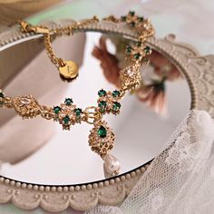 It's hard not to give in to the charm of the "Penelope" choker, designed to amaze and enchant those who watch you wear it, incredulous in the face of such splendor. Made with 14k gold-plated brass components embellished with splendid cubic zirconia crystals, emerald green dominates the scene and alternates with luminous crystals with refined shapes. The main pendant consists of an emerald green teardrop connector and a Mallorca teardrop pearl. The chain is made of 14k gold plated stainless steel Elegant 17 Jewels Choker As A Gift, Elegant Gold Emerald Necklace For Party, Green Metal Choker For Party, Elegant May Birthstone Necklace For Party, Elegant May Birthstone Party Necklace, Emerald Necklaces With Jewels For Party, Emerald Jeweled Necklaces For Party, Green Metal Choker Jewelry, May Birthstone Party Jewelry