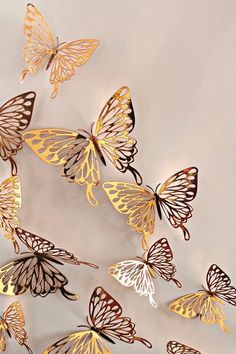 a group of butterflies flying in the air with gold and white colors on their wings