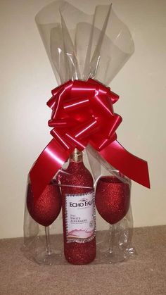 a bottle and two wine glasses wrapped in red ribbon