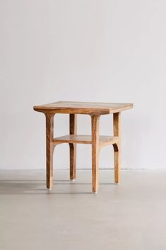 a wooden table sitting on top of a cement floor next to a white wall in an empty room