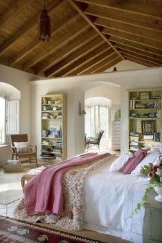 a bedroom with a large bed and wooden ceiling