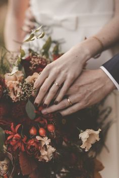 the bride and groom are holding each other's hands with their wedding bouquets