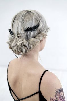 the back of a woman's head with braids in her hair and tattoos