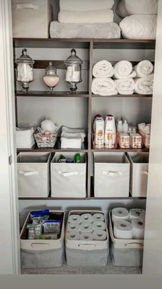 an organized closet with toiletries, towels and other items in bins on the shelves