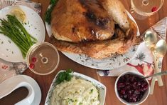 a large turkey sitting on top of a white plate next to other plates and silverware