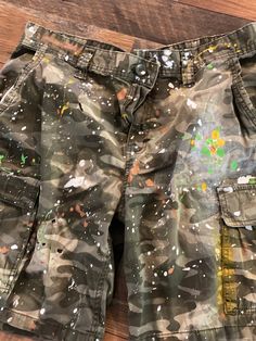 These camo shorts are absolutely perfect.  Side-pocket styling and faded provide a little attitude.  Add to that the paint splatters and you'll be hitting it out of the park. Pair them up with your favorite tee and some flip flops and you're readyfor anything. These are handmade items, so color variations may differ slightly.  #jeanshorts #camo #bermudashorts #splatterjeans #shortsandflipflops #summerfun #summervibes #shopsmall #tiedye #bleachdye #vintagefeel  DETAILS Size: 36 Color: Camo Detail Green White Paint, Army Shorts, Army Fatigue, Tie Dye Jeans, Paint Splatters, Big Shirt, Camo Shorts, Bleach Dye, Camo Pants