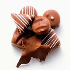 chocolate candies are arranged on top of each other, with leaves and nuts in the middle