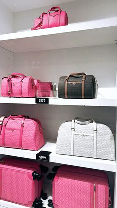 pink and white luggage on shelves in a store