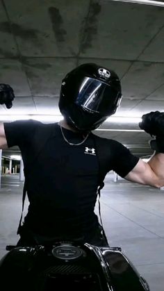 a man riding on the back of a motorcycle wearing a helmet and holding his arms out