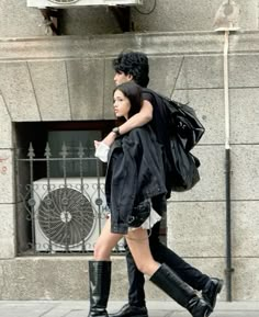 a man and woman are walking down the street with their backs to each other,