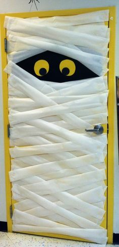 a door decorated to look like a monster with yellow eyes and white paper wrapped around it