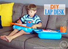 a young boy sitting on a couch with a book and pencils in his lap