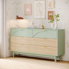 a green dresser with wicker drawers in front of a wallpapered wall and door