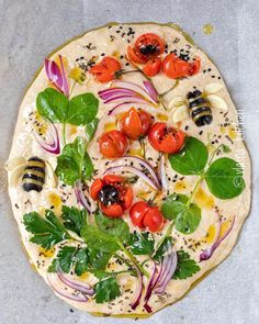 an uncooked pizza topped with tomatoes, onions and herbs