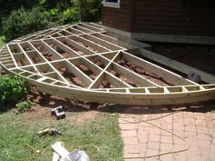 a wooden boat sitting on top of a field next to a brick walkway and building materials