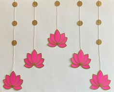 pink and gold paper flowers hanging from strings on a white wall with circles around them