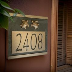 a house number sign mounted to the side of a building with two turtles on it