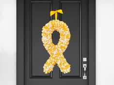 a yellow and white wreath is hanging on the front door to show support for those who have lost their lives