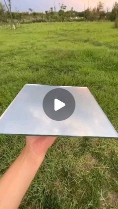 someone is holding up a glass plate in the middle of a field with green grass