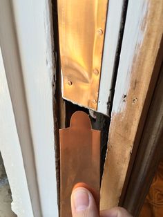 a hand holding a piece of metal in front of a door