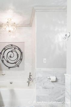 a bathroom with white walls and marble flooring, including a bathtub in the center