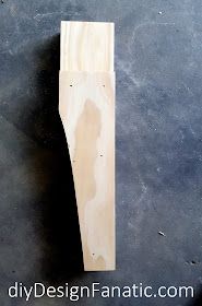 a piece of wood sitting on top of a black floor next to a knife blade