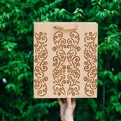 a person holding up a cardboard box with an intricate design on it