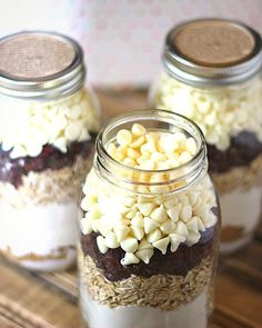 three jars filled with food sitting on top of a wooden table