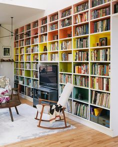 a living room filled with lots of book shelves next to a flat screen tv on top of a wooden table