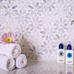 two white towels sitting next to each other on top of a counter with flowers in the background