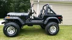 a black jeep parked in front of a house on the grass next to a tree