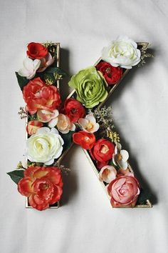 the letter k is decorated with flowers and greenery to spell it's name