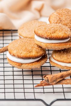 cinnamon spice cookies with white frosting and cinnamon sticks on a cooling rack in front of them