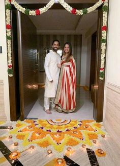 a man and woman standing in front of an entrance decorated with flowers, garlands and candles