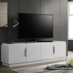 a large flat screen tv sitting on top of a white entertainment center next to a window