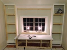 an unfinished room with two windows and shelves