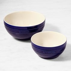 two blue and white bowls sitting next to each other on top of a marble counter