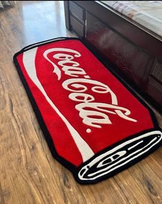 a coca - cola rug is laying on the floor next to a bed