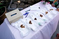 a table topped with lots of white bags filled with dirt next to a vase full of flowers